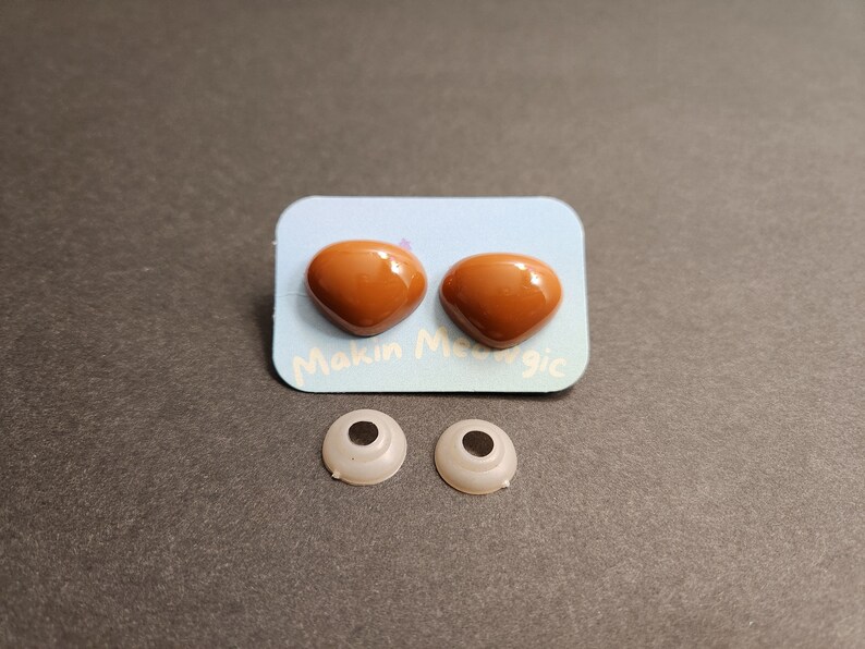 May include: Two brown plastic safety eyes with a white backing card that says "Makin' Magic".