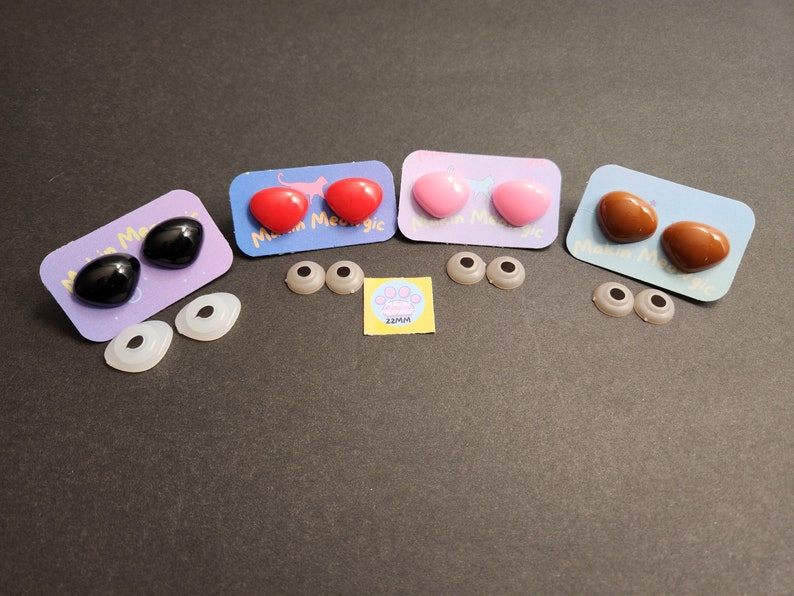 May include: Four pairs of plastic safety eyes for crafts, in black, red, pink, and brown. Each pair is packaged on a card with the text "Mini Magic" and a paw print with the text "22MM".