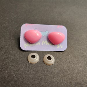 May include: Two pink plastic safety eyes and two white plastic safety eye sockets. The safety eyes are on a purple card with the text "Make Me Magic".