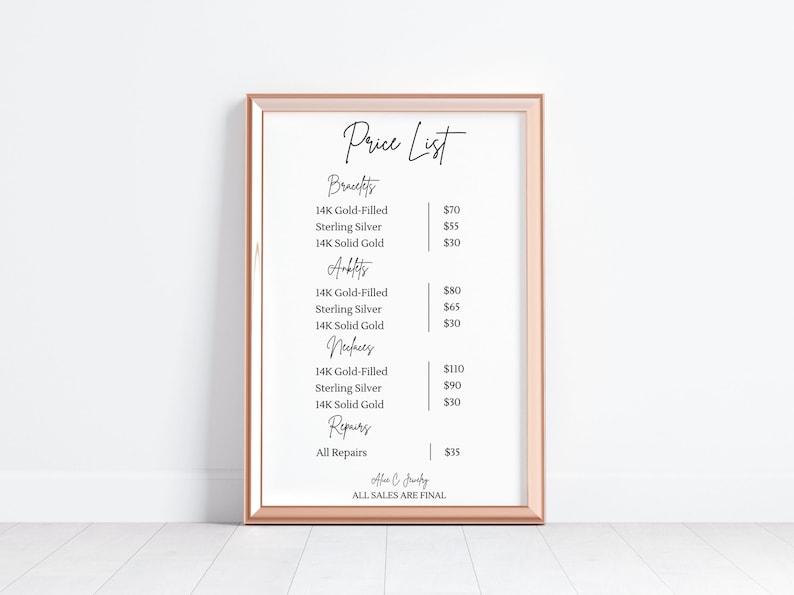 Op de afbeelding: Een ingelijste prijslijst voor sieraden, met categorie&euml;n zoals armbanden, enkelbanden, kettingen en reparaties. De lijst bevat prijzen voor 14K goudgevulde, sterling zilveren en 14K massief gouden items. De lijst heeft een ros&eacute;gouden frame.