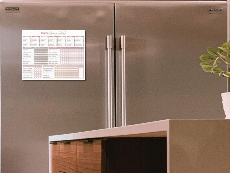 May include: A white magnetic cleaning schedule chart with the text "Home Cleaning Schedule" in pink script. The chart is attached to a stainless steel refrigerator.