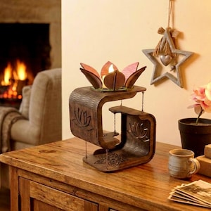 May include: A dark brown wooden tiered display stand featuring laser-cut lotus flower motifs on the sides and base. The top tier holds a decorative lotus flower candle holder with pink-tipped petals and a small white light in the center.