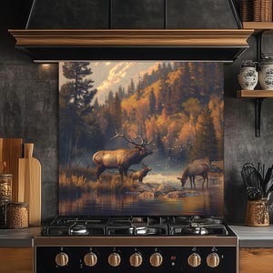 Puede incluir: Un protector de salpicaduras de cocina decorativo con un paisaje escénico con alces cerca de un cuerpo de agua. La obra de arte muestra un bosque con colores otoñales, creando una estética natural y rústica. El protector de salpicaduras está instalado sobre una cocina de gas negra.