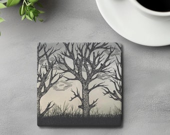 Pode incluir: Um porta-copos quadrado com uma ilustração a tinta preta e branca de árvores nuas e sem folhas contra um céu cinzento claro. O design inclui uma faixa horizontal escura e sólida na parte inferior que representa relva e ramos detalhados.
