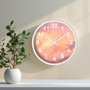 May include: A white round clock with a pink and orange sunset sky background. The clock face has black hands and white numbers.