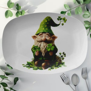 May include: White oval serving platter with a green leprechaun holding shamrocks. The leprechaun is wearing a green hat with gold stars and a green beard.