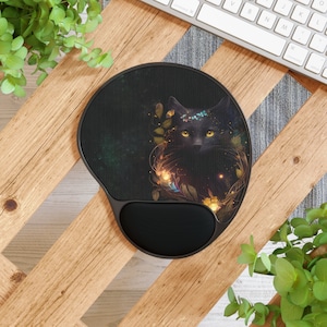 May include: Black cat mouse pad with a floral design and a black wrist rest. The cat has a crown of flowers and glowing eyes.