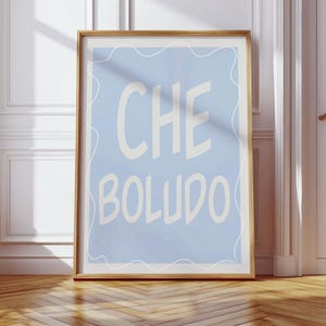 May include: A framed print with a light blue background and white text that reads "CHE BOLLUDO".