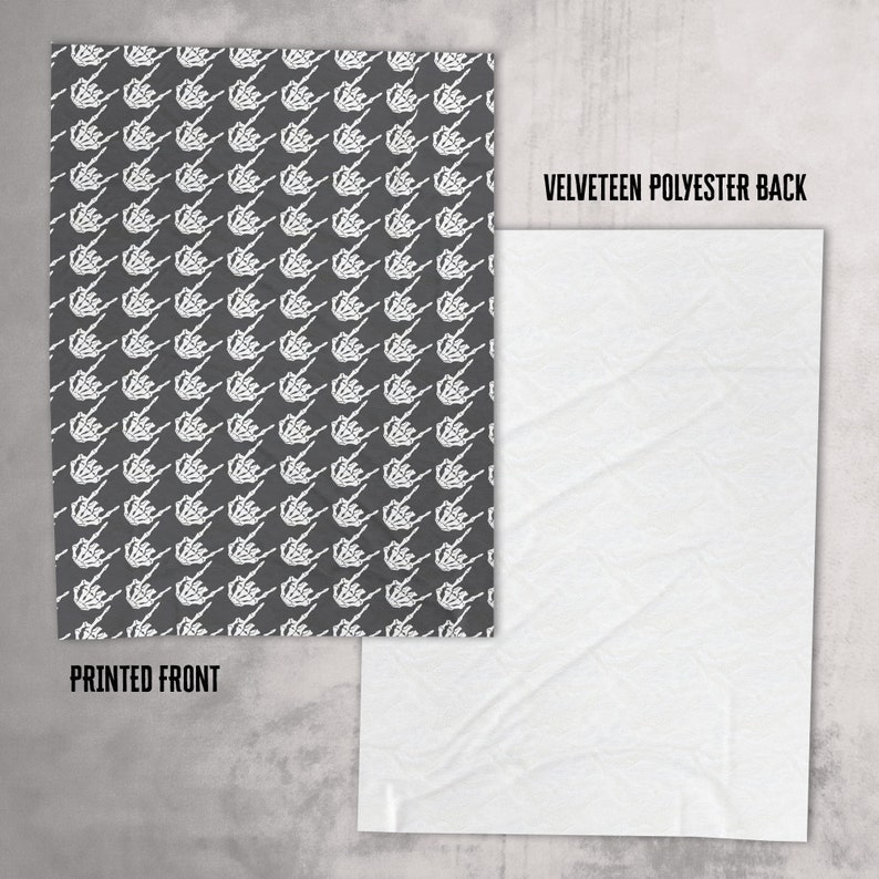 May include: A black and white patterned fabric with a skeleton hand design. The fabric is printed on one side and has a plain white velvety polyester back.