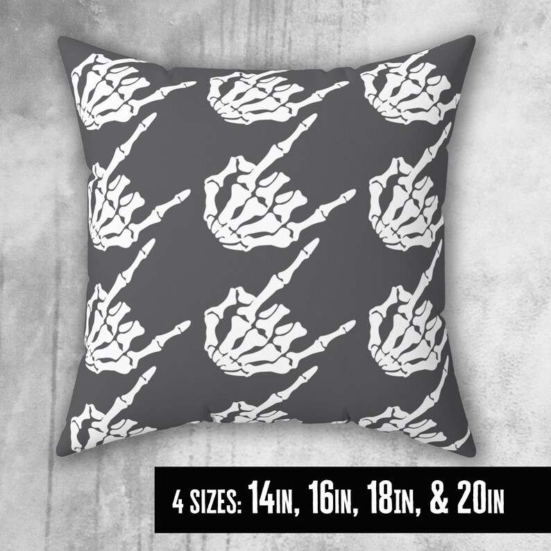 May include: A gray throw pillow with a white skeleton hand pattern. The hand is making a middle finger gesture. The pillow is available in four sizes: 14 in, 16 in, 18 in, and 20 in.