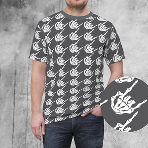 May include: Gray t-shirt featuring a repeating pattern of white skeleton hands making the rock on gesture. The shirt has a crew neck and short sleeves. A close-up of the hand gesture is in the lower right corner.