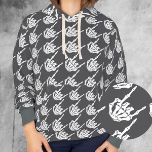 May include: A gray hoodie with a repeating pattern of white skeleton hands making a rock and roll gesture. The hoodie has a drawstring hood, a front pocket, and gray cuffs. The design is a bold statement piece.
