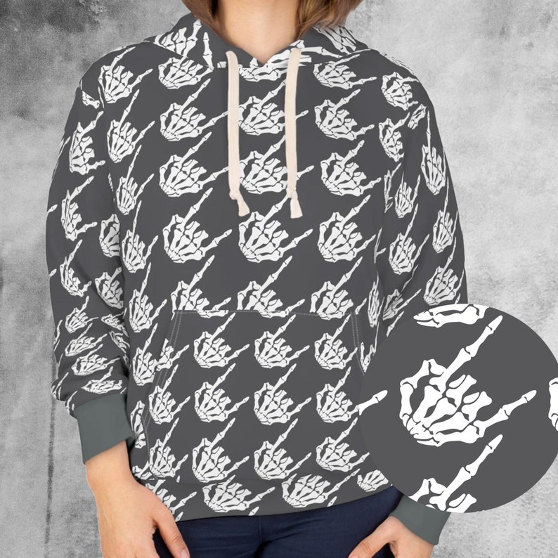 May include: A gray hoodie with a repeating pattern of white skeleton hands making a rock and roll gesture. The hoodie has a drawstring hood, a front pocket, and gray cuffs. The design is a bold statement piece.