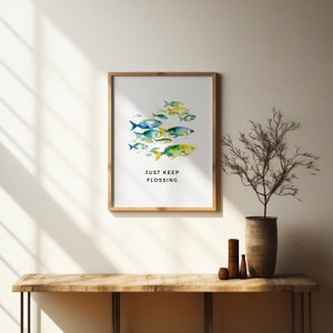 May include: A framed print with a watercolor illustration of a school of colorful fish swimming in a circle. The text "JUST KEEP FLOSSING" is printed below the fish.