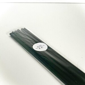 May include: A packet of black incense sticks, sealed in clear plastic. A white circular label with Japanese text is visible on the packaging. The sticks are arranged neatly. The background is plain white.