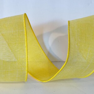 May include: A bright yellow ribbon with a woven, textured fabric appearance and a solid yellow stitched edge. The ribbon is arranged in a loose, flowing S-curve shape, showcasing its semi-translucent quality and consistent vibrant color throughout.