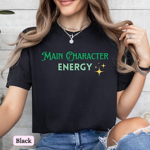 May include: Black t-shirt with the text "Main Character Energy" in green and yellow.