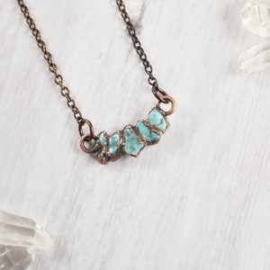 May include: A copper chain necklace with a pendant made of turquoise stones. The stones are irregular in shape and have a rough, natural texture.