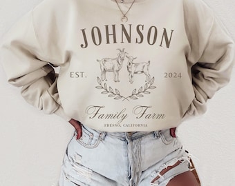 Może przedstawiać: Beżowa bluza z nadrukiem "JOHNSON Family Farm EST. 2024 FRESNO, CALIFORNIA" i grafiką dwóch kóz.