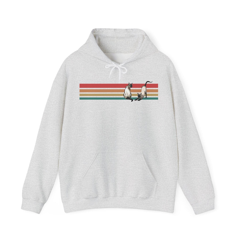 May include: A light gray hoodie with a kangaroo pocket and drawstring hood. The front features a horizontal design with red, orange, and green stripes, and two Siamese cats. The cats are in a playful pose.