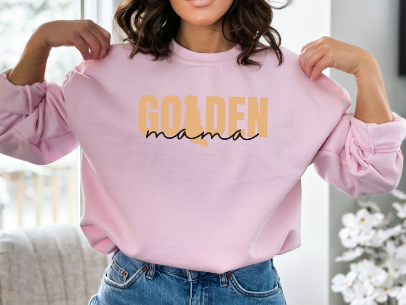 May include: A pink sweatshirt with the text "Golden mama" in orange and black lettering.