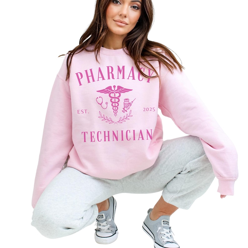 May include: Pink sweatshirt with the text "Pharmacy Technician" and a pink caduceus symbol with the text "Est. 2025".