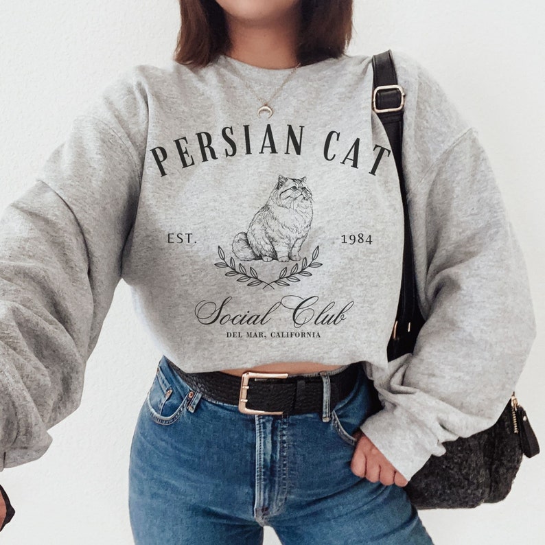 May include: Grey cropped sweatshirt with a black graphic print of a Persian cat, the text "Persian Cat", "Est. 1984", "Social Club", and "Del Mar, California".