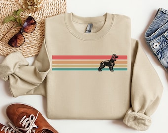 May include: A tan sweatshirt with a retro-style rainbow stripe design and a black silhouette of a cocker spaniel dog.