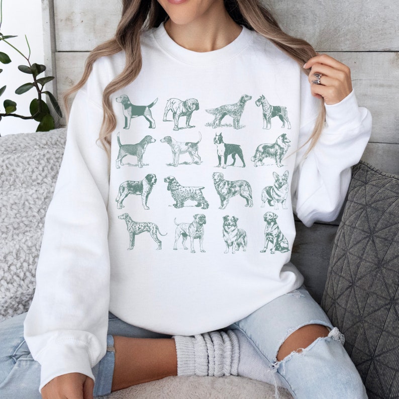 May include: White sweatshirt with a green print of various dog breeds. The print is arranged in a grid pattern.