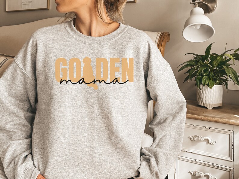 May include: A gray sweatshirt with the text "GOLDEN mama" in black and tan lettering.