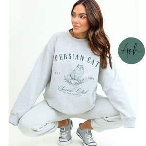 May include: A grey sweatshirt with the text "Persian Cat Social Club Est. 1984 Del Mar, California" and a drawing of a Persian cat.