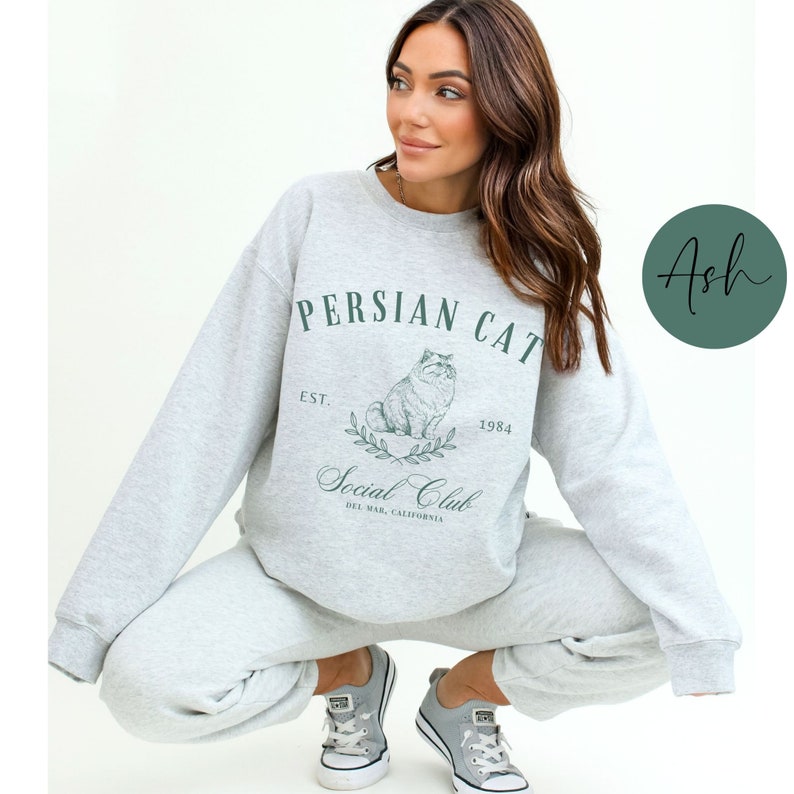 May include: A grey sweatshirt with the text "Persian Cat Social Club Est. 1984 Del Mar, California" and a drawing of a Persian cat.