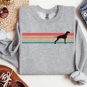 May include: A gray sweatshirt with a retro-style rainbow stripe design and a black silhouette of a German Shorthaired Pointer dog.