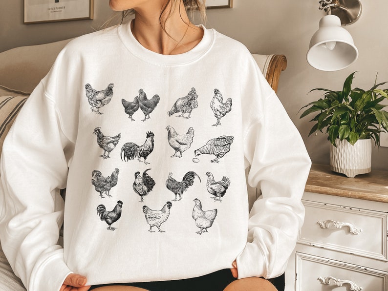 May include: White sweatshirt with a black and white illustration of various chickens and roosters.