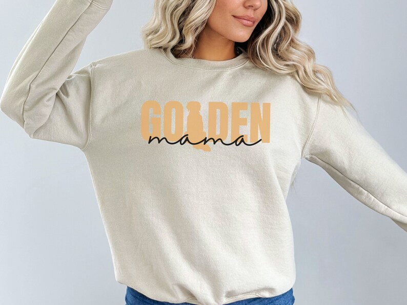 May include: A beige sweatshirt with the text "GOLDEN mama" in orange and black lettering.