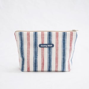 May include: A white, red, and blue striped zippered pouch with a label that reads "Sewing Stroll".