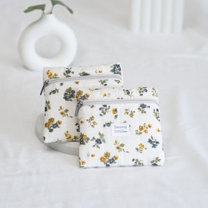 May include: Two small white zippered pouches with a floral print in shades of blue, yellow, and green. The pouches have a white label that reads "Sewing Stroll".