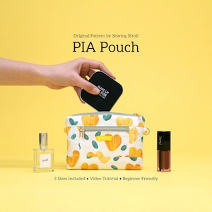 May include: A white and yellow patterned PIA Pouch with a gold zipper, holding a black compact. A perfume bottle and a tube of lip gloss sit beside the pouch. Text reads "PIA Pouch" and "3 Sizes Included".