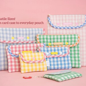 Puede incluir: Una colecci&oacute;n de bolsos de cuadros en varios tama&ntilde;os, desde tarjeteros hasta bolsos de uso diario. Los bolsos son azules, rosas, verdes y amarillos, con ribetes y cierres a juego. El texto dice "Versatile Sizes! From card case to everyday pouch".
