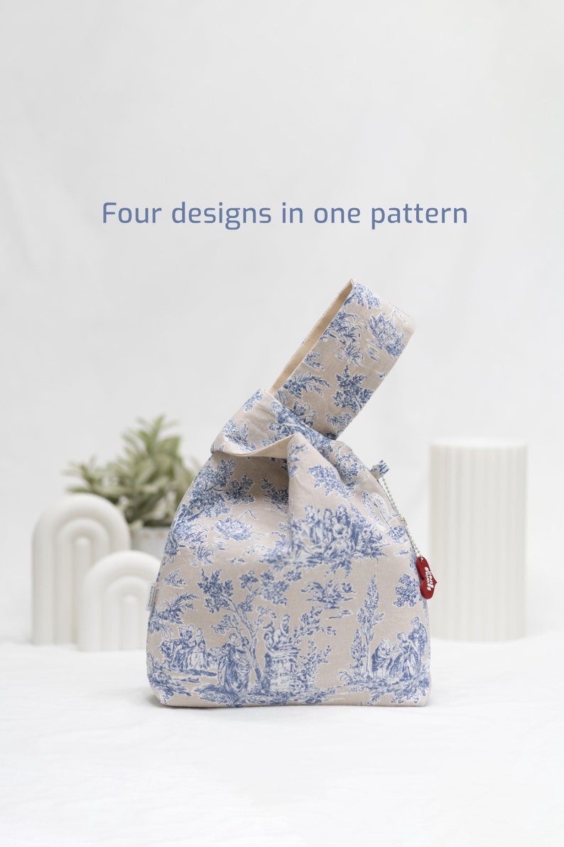 May include: A beige fabric tote bag with a blue and white floral pattern. The bag has a knotted handle and a small red tag that says "stitch".