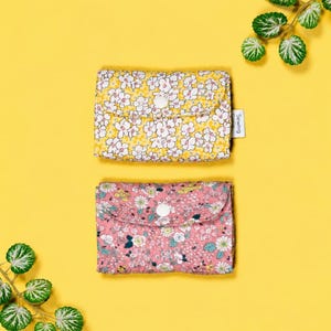 May include: Two rectangular fabric pouches with snap closures. One pouch features a yellow background with white floral patterns, and the other has a pink background with multi-coloured floral prints. A small white tag reads Sewing Glory.