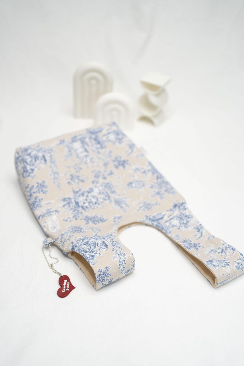 May include: A beige tote bag with a blue floral pattern. The bag has a small red heart-shaped tag with the text "Sewing Stuff" on it.