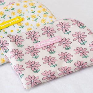 May include: Three pink and white floral zippered pouches with the text "Sewing Stroll" on each pouch.