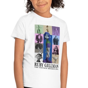 May include: White t-shirt with a colorful graphic of characters from the movie "Ruby Gillman, Teenage Kraken". The text "Ruby Gillman, The Teenage Kraken Era" is printed below the graphic.