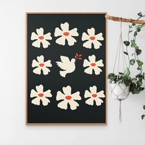 May include: A framed print with a black background featuring a white dove carrying an olive branch and surrounded by white flowers with red centers.