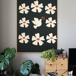 May include: A framed print with a black background and white flowers with red centers. A white dove with an olive branch in its beak flies through the center of the print.
