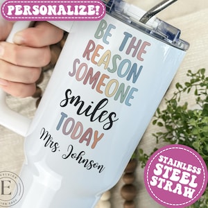 May include: White insulated tumbler with a handle, featuring the text "BE THE REASON SOMEONE smiles TODAY Mrs. Johnson" in pastel colors. Includes a stainless steel straw and a "PERSONALIZE!" sticker.