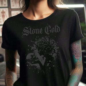 Könnte beinhalten: Schwarzes T-Shirt mit einem grafischen Druck einer Frau mit langen Haaren, die einen Schädel hält. Der Text "Stone Cold" ist über dem Grafikdruck gedruckt.