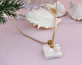 May include: A gold chain necklace with a square-shaped pendant made of white mother-of-pearl tiles.