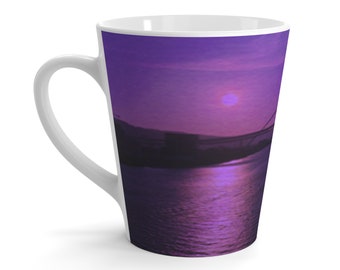 Könnte beinhalten: Eine weiße Keramiktasse mit einem aufgedruckten lila Sonnenuntergangs-Motiv. Die Szene zeigt eine Brücke, die vor dem Sonnenuntergang silhouettiert ist, mit einer großen, strahlenden Sonne am Himmel.
